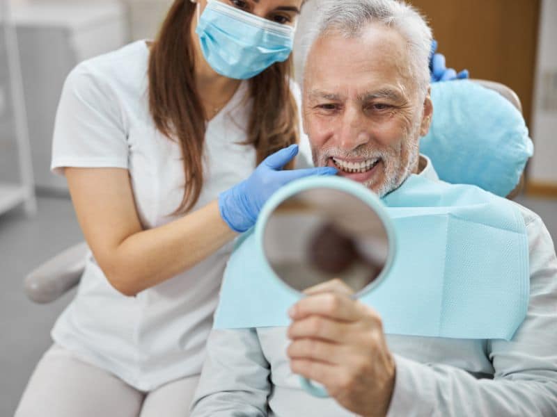 A patient admiring their new smile after getting dental implants in Cherry Hill, NJ.